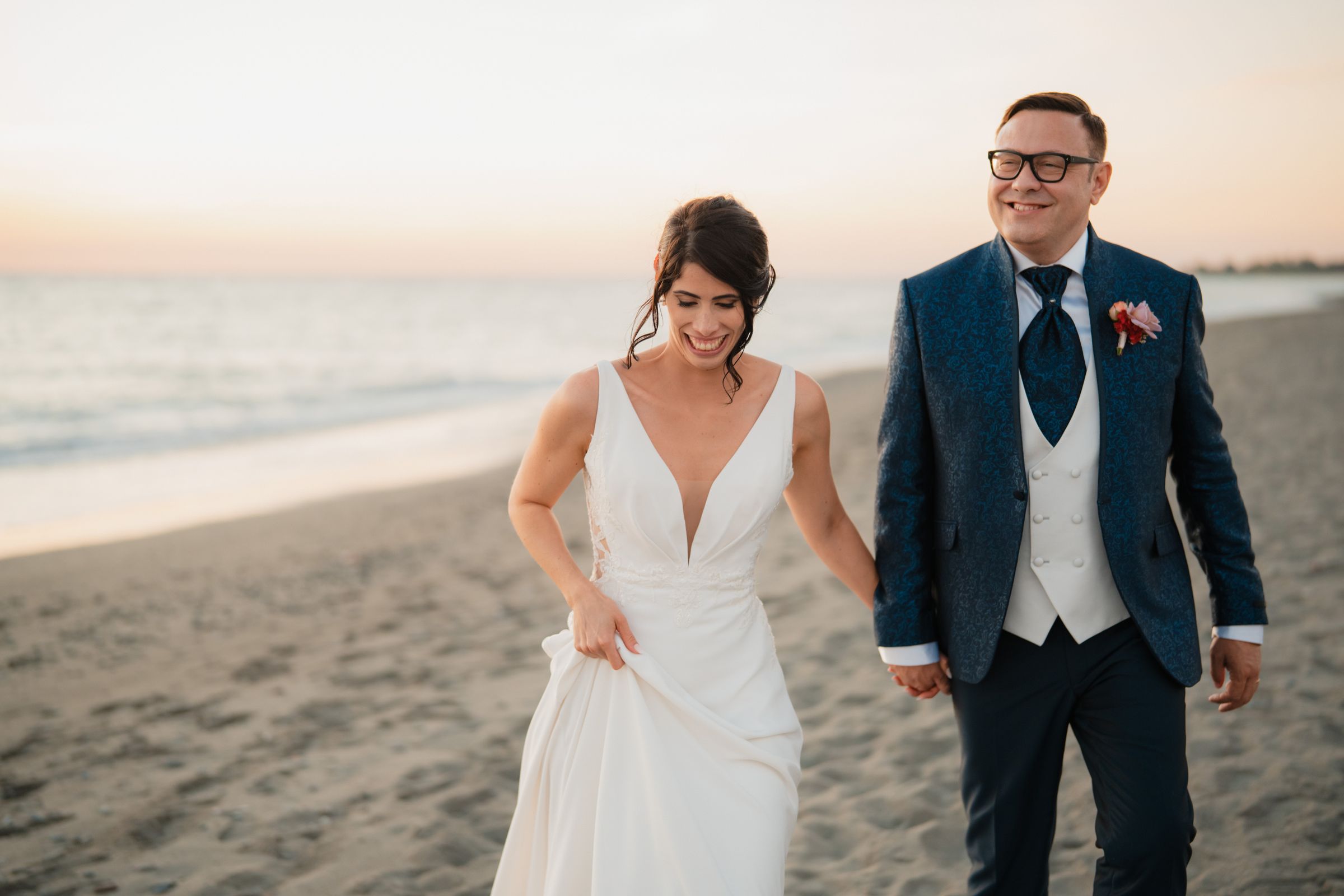 Casal caminhando junto na praia no dia de um casamento